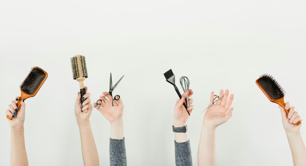 Gestionale per saloni di parrucchieri. L'immagine mostra le mani di un team di parrucchieri che impugnano gli strumenti tipici del proprio lavoro: forbici, spazzole e pennelli.